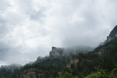 mountains with trees under cloudy skies thumbnail