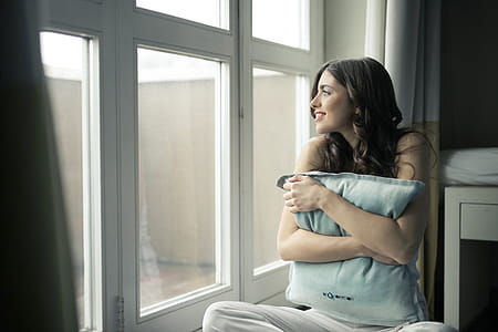 Black Haired Woman Hugging Gray Pillow Near Glass-panel Window thumbnail