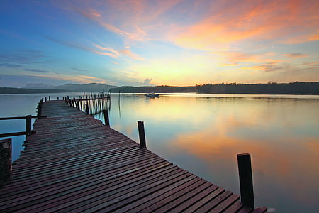 brown wooden dock surrounded with calm body of water during golden hour thumbnail