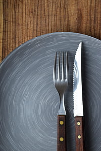 brown handled knife and fork on top of gray ceramic plate thumbnail