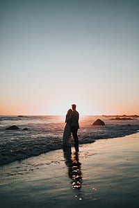 two person standing on the seashore during sunset thumbnail