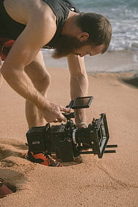 man holding video camera on brown sand thumbnail