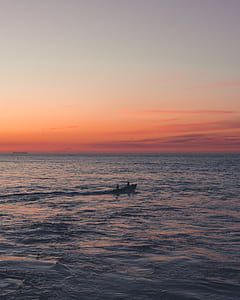 silhouette of two persons riding boat in middle of sea thumbnail