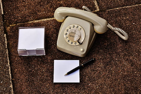 beige cradle telephone beside black twist pen on white paper thumbnail