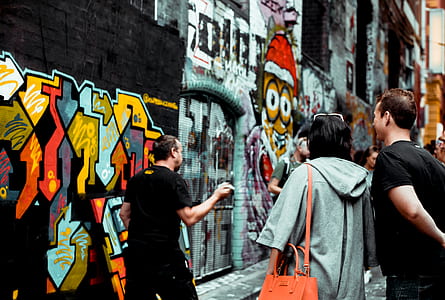 group of people standing in front graffiti wall thumbnail