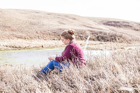 woman sitting on ground near road thumbnail