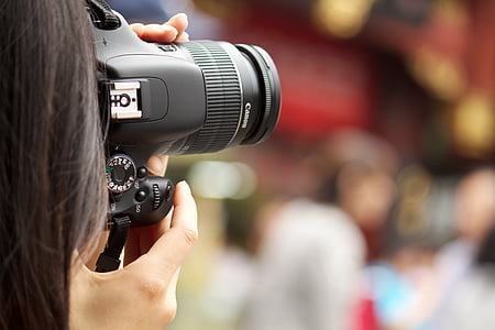 selective focus photography of woman holding DSLR camera thumbnail