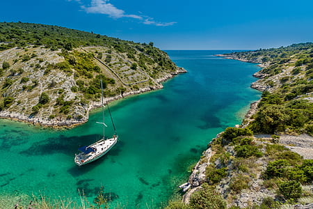 white yacht between the islands under sunny sky thumbnail