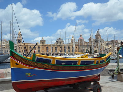 blue and multicolored wooden boat on black trailer near port during daytime thumbnail