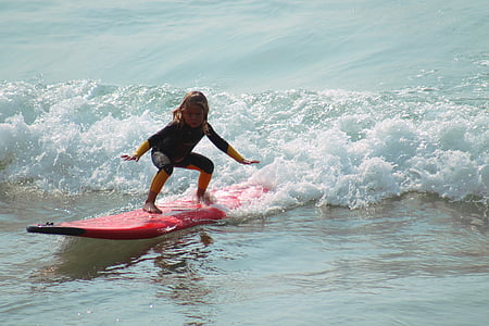 girl riding red surfboard in the ocean during daytime thumbnail