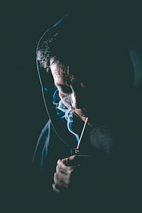 man in hood lighting cigarette smoke thumbnail