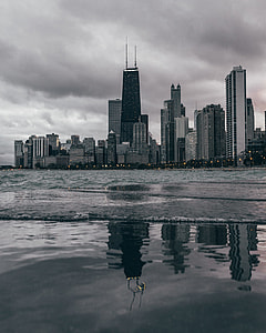grayscale photography of city building near body of water thumbnail