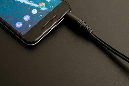 black earphone plugged in black Android smartphone thumbnail