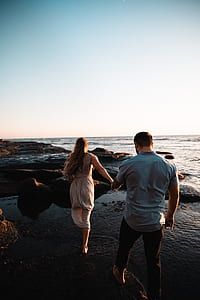 woman in gray dress holding hand of man in gray polo shirt thumbnail