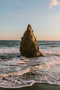 large brown rock in the middle of seashore thumbnail