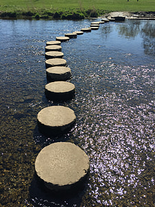 round gray concrete blocks place on body of water to create a pathway duty daytime thumbnail