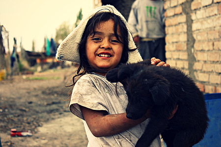 girl carrying black Labrador retriever puppy thumbnail