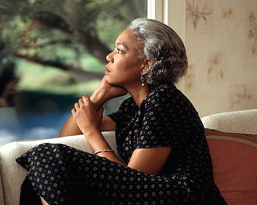 woman with black and gray short-sleeved dress sitting on gray fabric sofa thumbnail