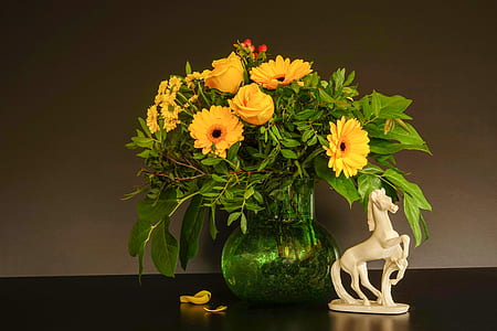yellow sunflowers in green vase beside white ceramic figurine thumbnail