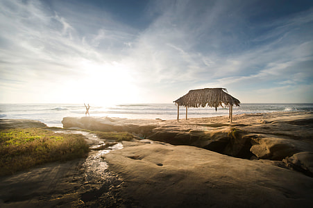 brown hut near rocky seashore thumbnail