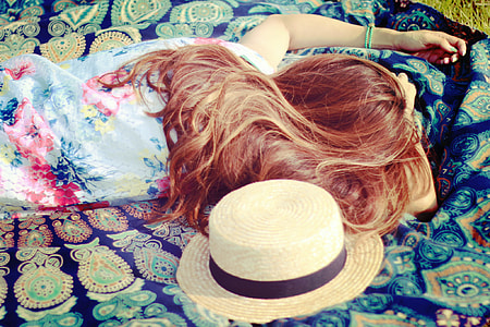 female in blue floral shirt laying on blue floral picnic mat with sunhat thumbnail