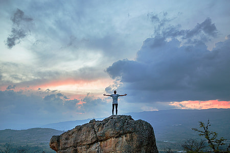 man in white shirt standing on brown rock thumbnail