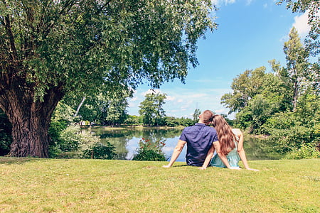 man and woman sitting on grass field during daytime thumbnail