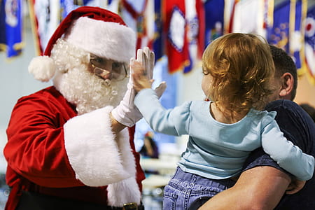 Santa Claus doing high five with girl carried by man during daytime thumbnail