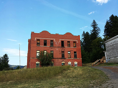 brown concrete 3-storey building beside gray road under blue sky at daytime thumbnail