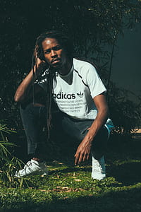 man kneeling on green grass near trees thumbnail