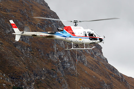 helicopter hovering near mountain thumbnail