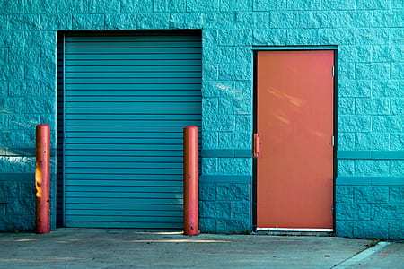 blue concrete building with blue and orange doors at daytime thumbnail
