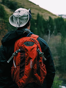man wearing black hooded jacket carrying red CamelBak backpack thumbnail