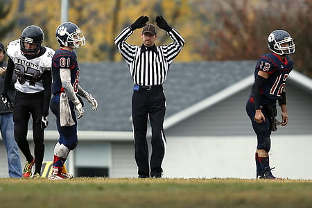 referee making hand gesture between football players thumbnail