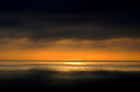 calm body of water under orange and yellow sky thumbnail