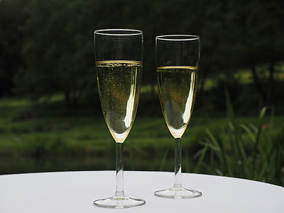 two clear champagne glasses with liquid on table thumbnail