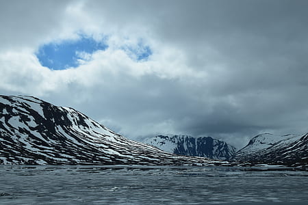 landscape photo of white and black mountain near body of water at daytime thumbnail