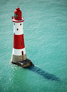 red and white lighthouse surrounded by body of water during daytime thumbnail