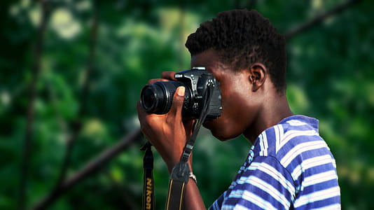 Man Wearing Blue And White Striped Shirt Using Nikon Camera thumbnail