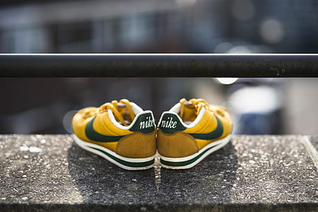 pair of yellow-and-green Nike low-top sneakers on gray surface selective focus photography thumbnail