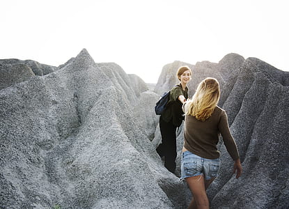 woman reaching other woman between rocks thumbnail