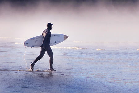 man holds surfboard at sea thumbnail