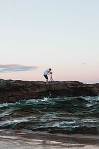 man holding camera near on body of water thumbnail