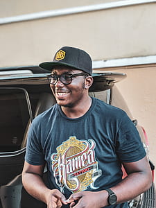 man wearing cap standing beside car thumbnail