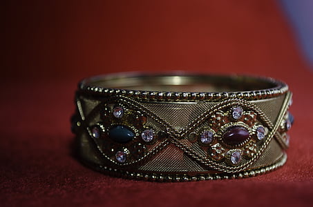 jeweled gold-colored bracelet on red textile thumbnail