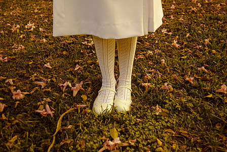 person standing on grass field with withered flowers thumbnail