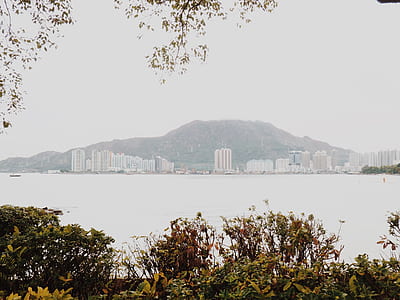 body of water near buildings and mountain at daytime thumbnail