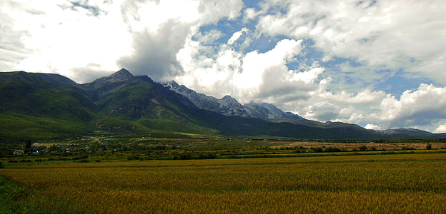 fields near mountain under cloudy sky thumbnail