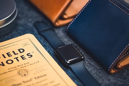space gray Apple Watch beside brown and black leather bifold wallets on table thumbnail