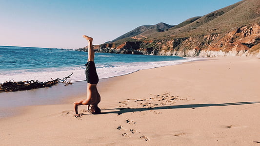 man standing on head on seashore thumbnail